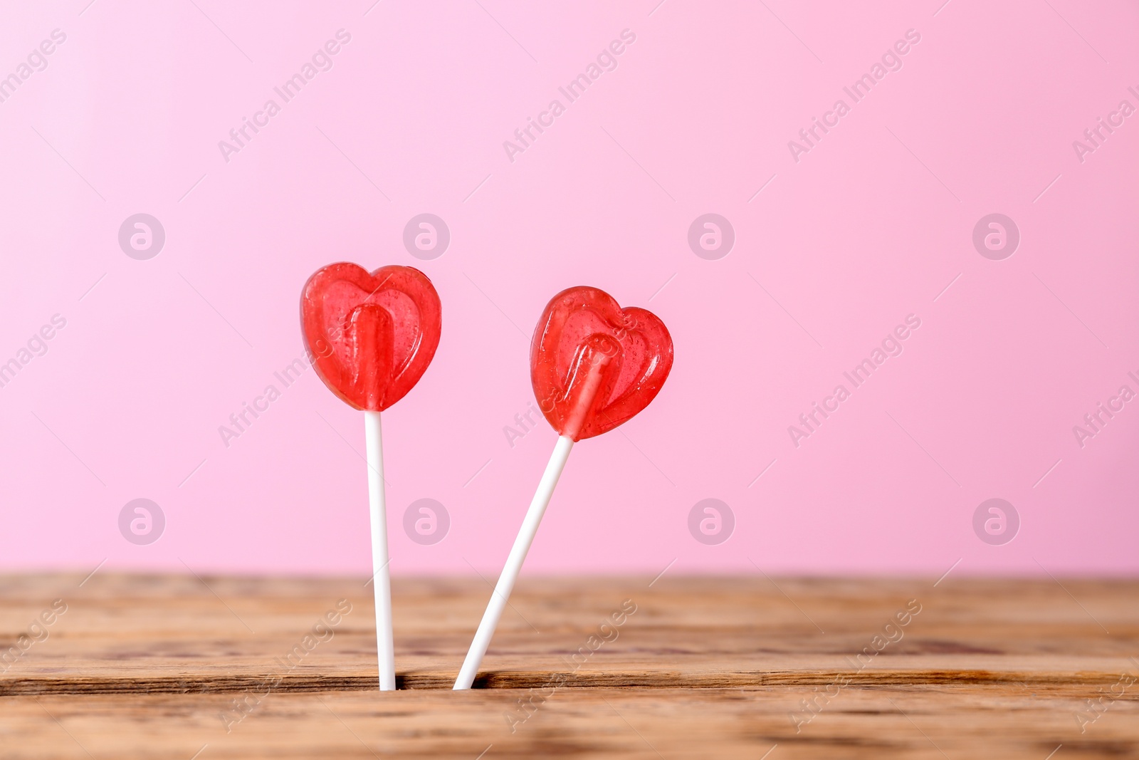 Photo of Heart shaped lollipops on color background, space for text. Sweet love