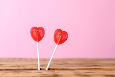 Photo of Heart shaped lollipops on color background, space for text. Sweet love