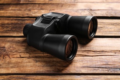 Photo of New binoculars on wooden table. Optical instrument