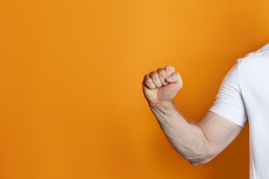 Young man showing clenched fist on color background. Space for text