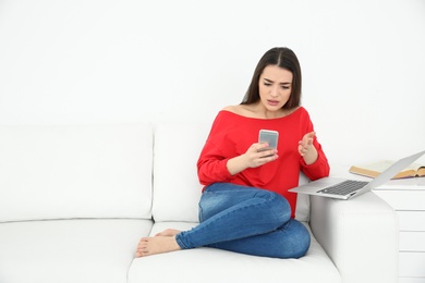 Photo of Young woman using mobile phone and laptop at home