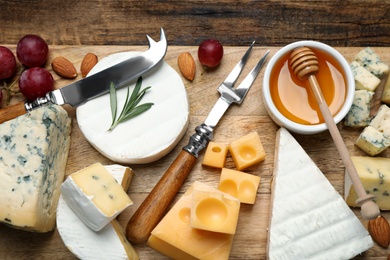 Flat lay composition with different sorts of cheese and knives on wooden table