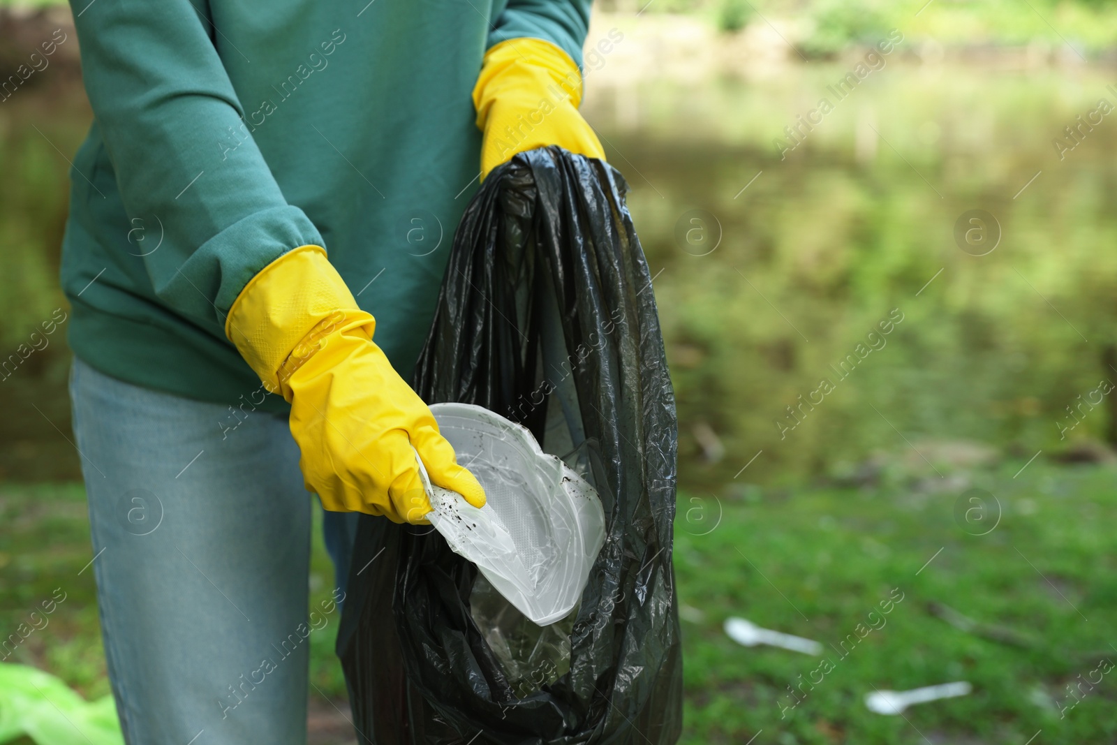 Photo of Woman with plastic bag collecting garbage in park, closeup. Space for text