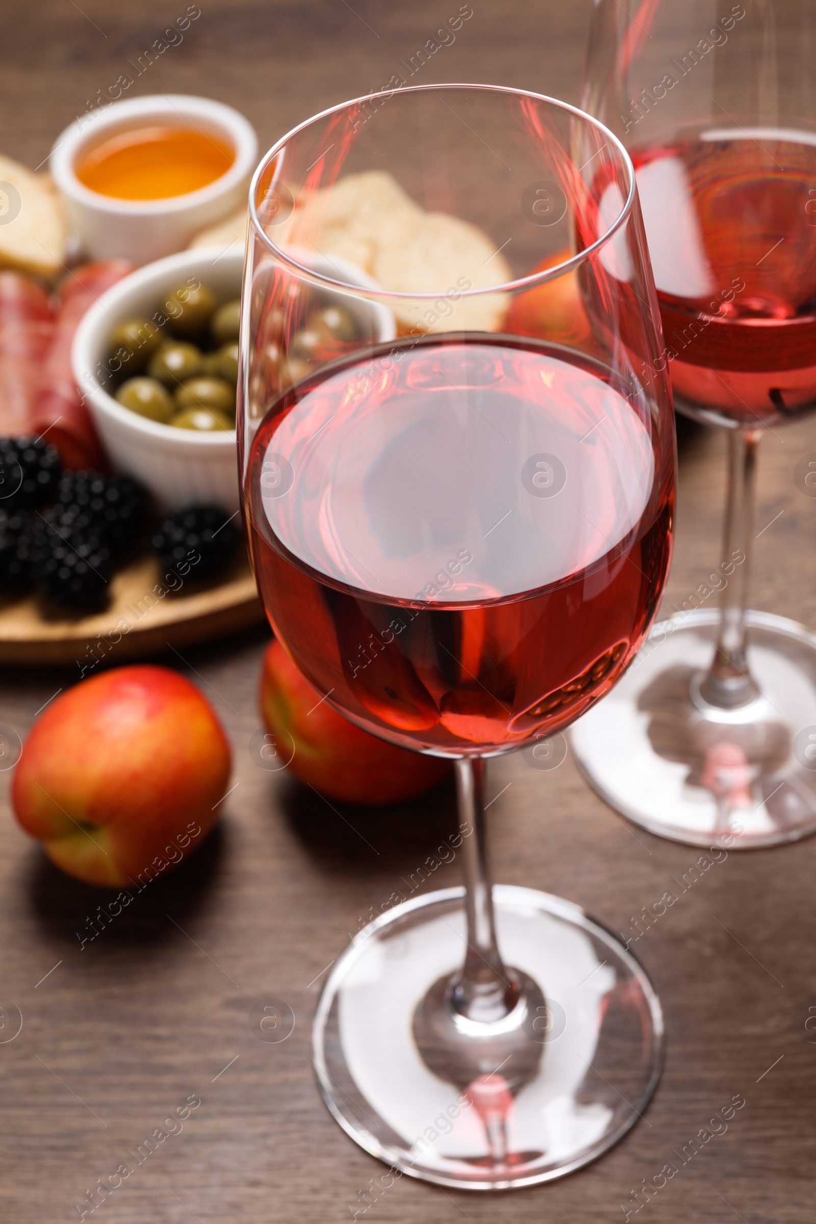 Photo of Delicious rose wine and snacks on wooden table, closeup