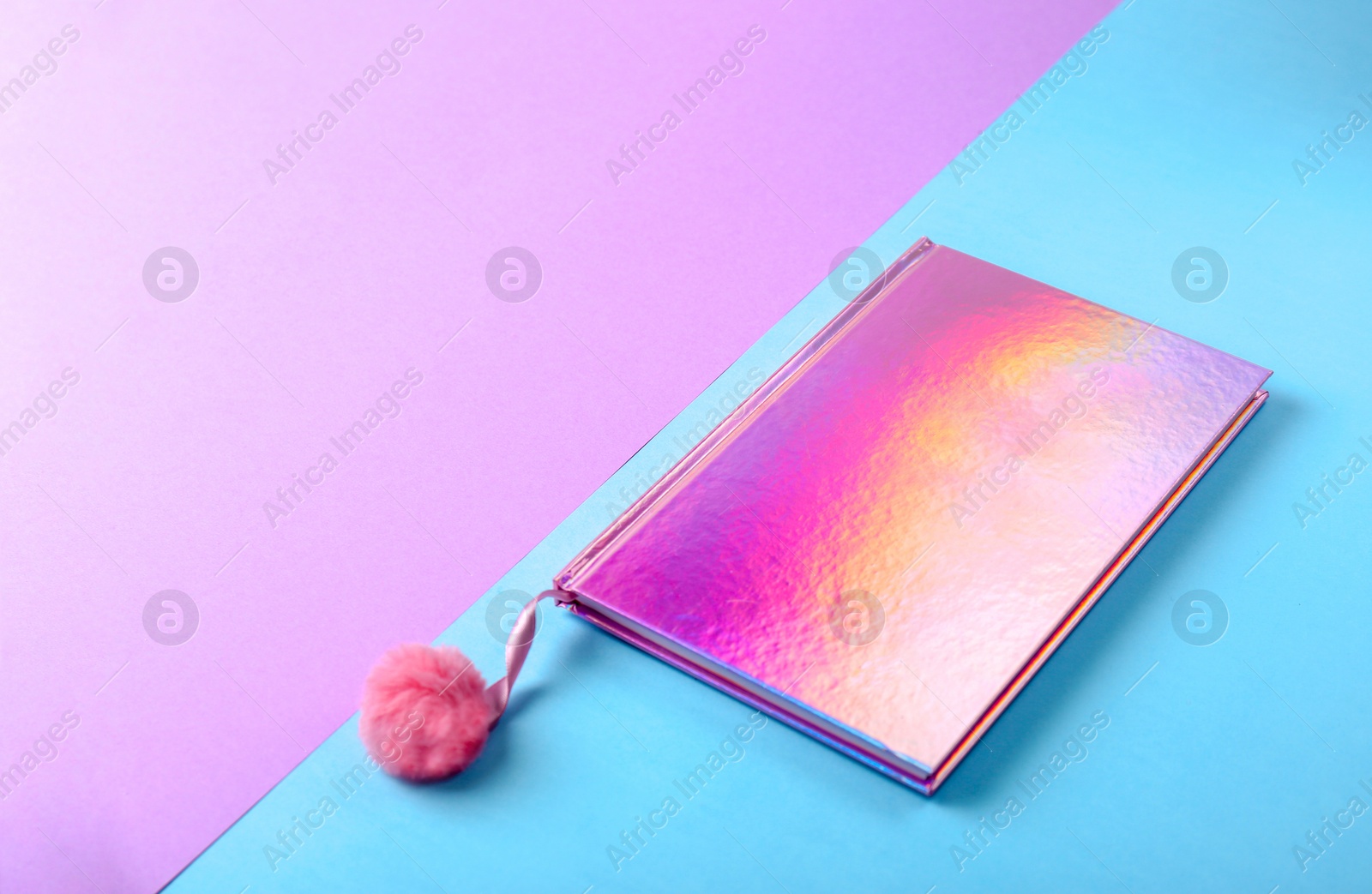 Photo of Stylish female notebook with pink pompom on color background. Space for text