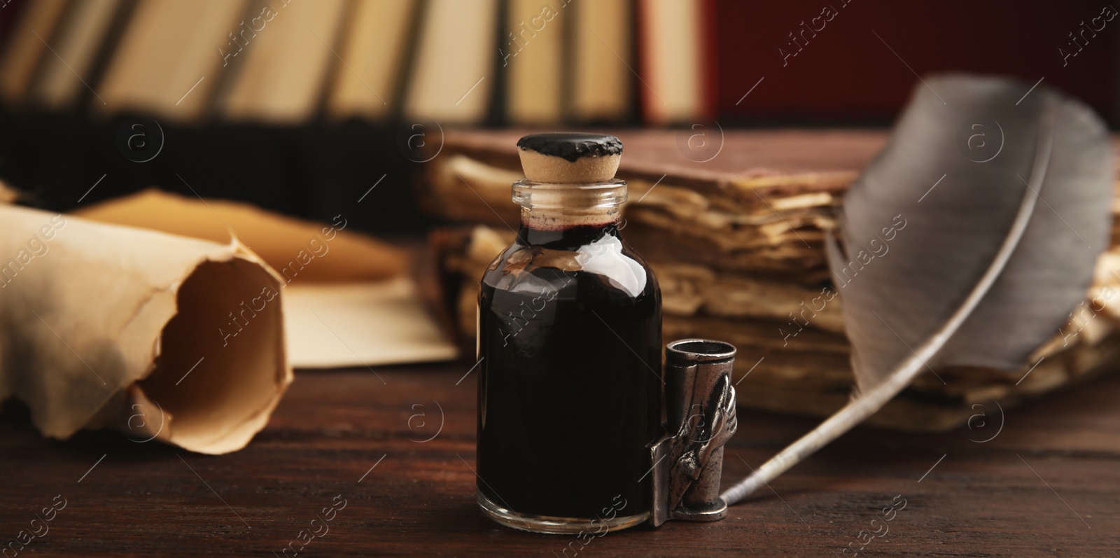 Image of Quill and bottle of ink on wooden table, closeup view. Banner design