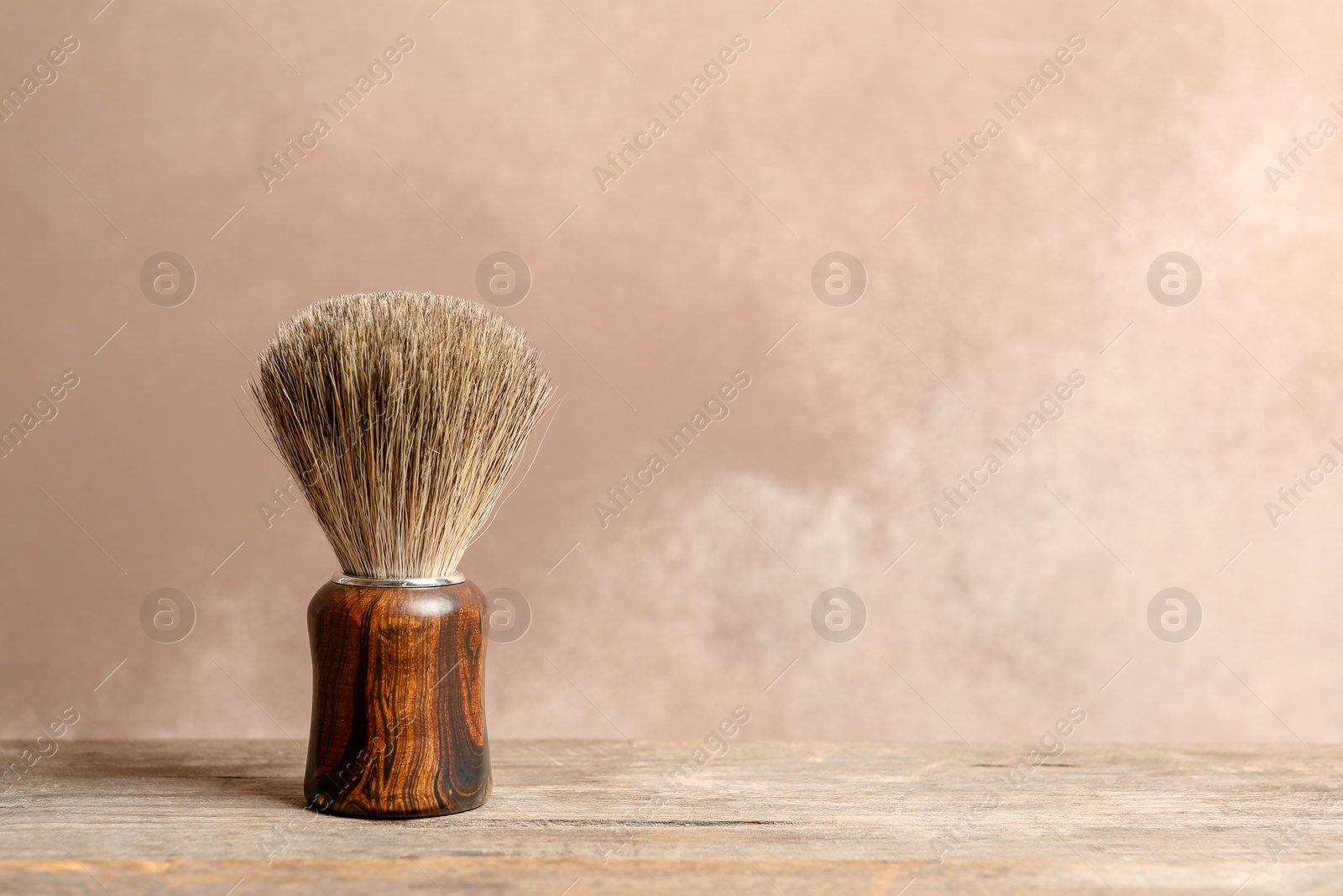 Photo of Shaving brush on table against color background with space for text