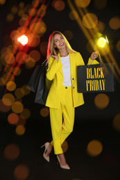 Image of Black Friday sale. Happy young woman with shopping bags 
