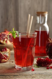 Photo of Tasty pomegranate juice in glass and fresh fruits on wooden table