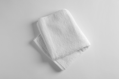 Photo of Folded soft terry towel on light background, top view