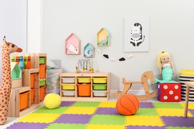 Photo of Cute child's room interior with toys and modern furniture