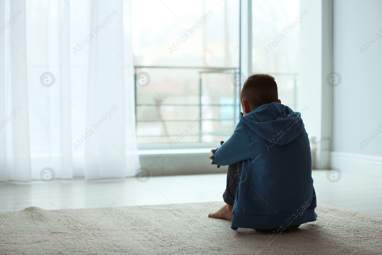 Photo of Upset boy sitting near window indoors. Space for text