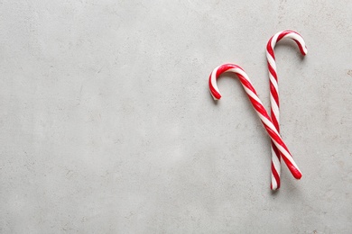 Photo of Candy canes on light grey background, flat lay with space for text. Traditional Christmas treat