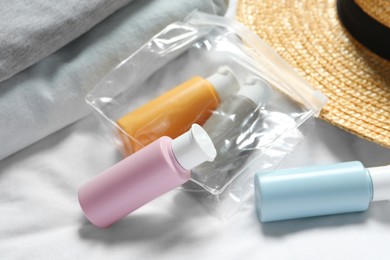 Photo of Cosmetic travel kit. Plastic bag with small containers of personal care products on bed