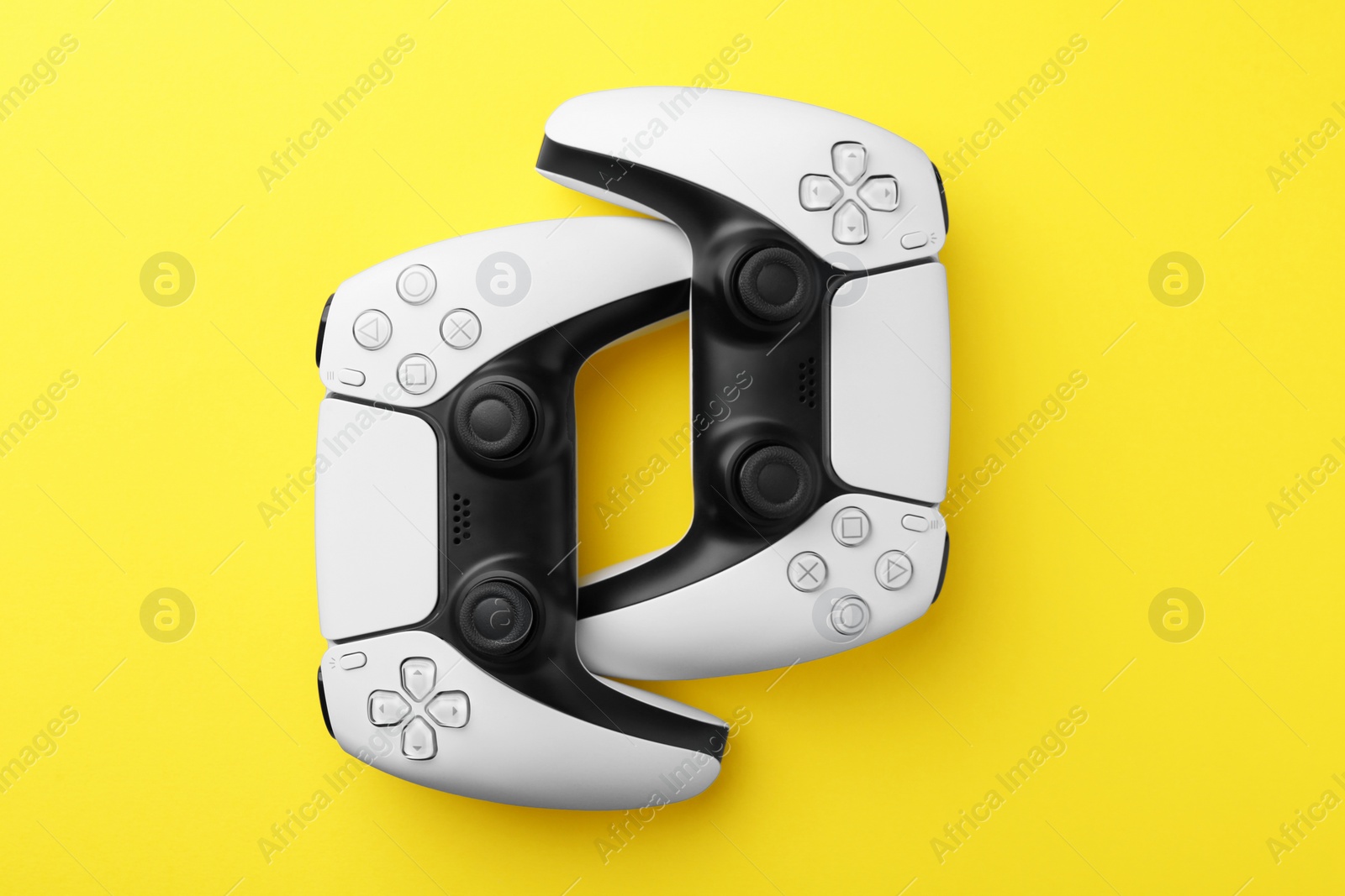 Photo of Wireless game controllers on yellow background, flat lay