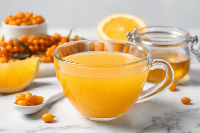 Fresh sea buckthorn tea on white marble table, closeup