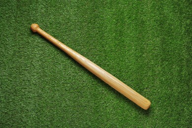 Photo of Wooden baseball bat on green grass, top view. Sports equipment