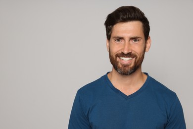 Portrait of happy bearded man on grey background. Space for text