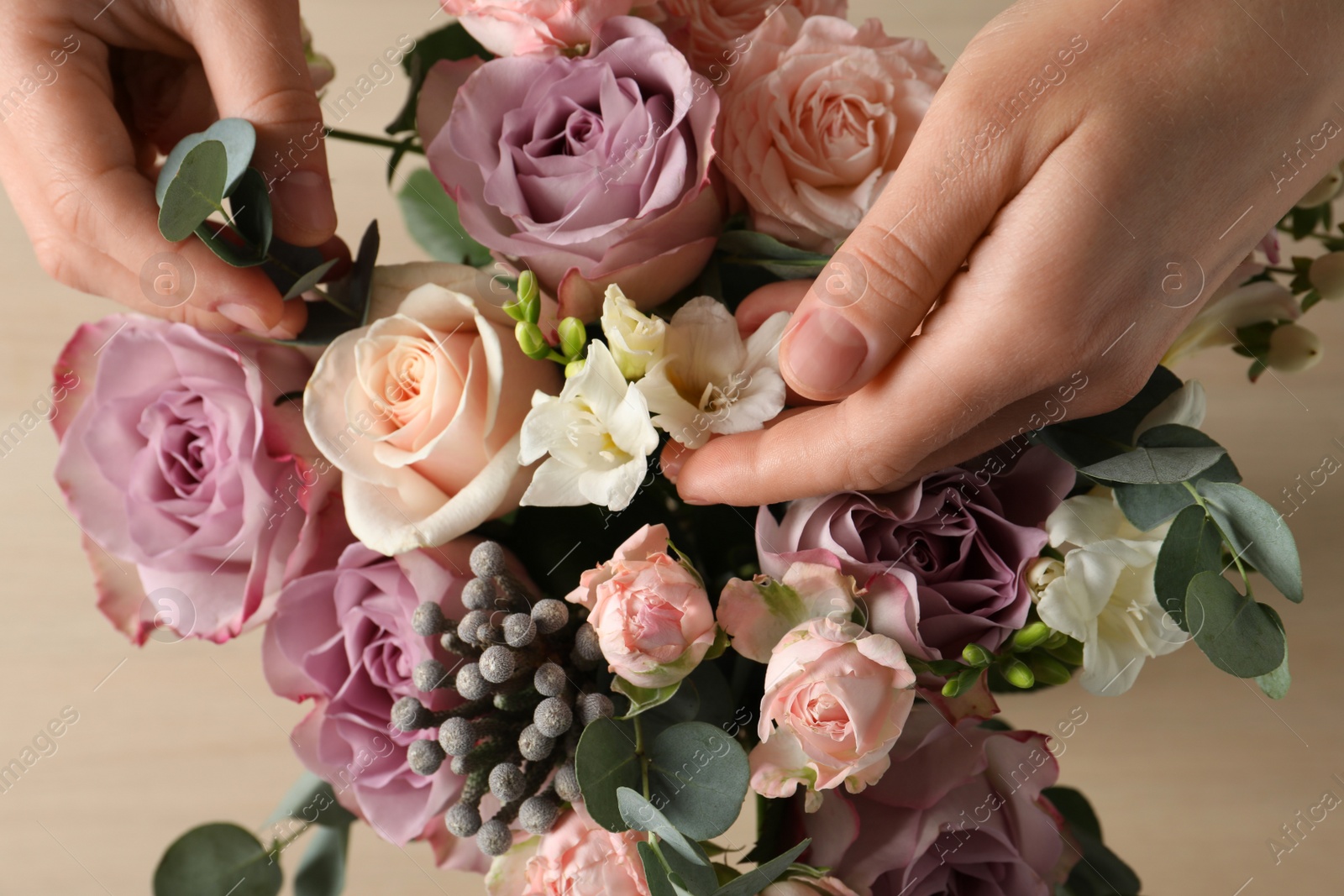 Photo of Florist creating beautiful bouquet at table, top view