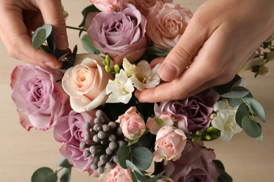 Florist creating beautiful bouquet at table, top view