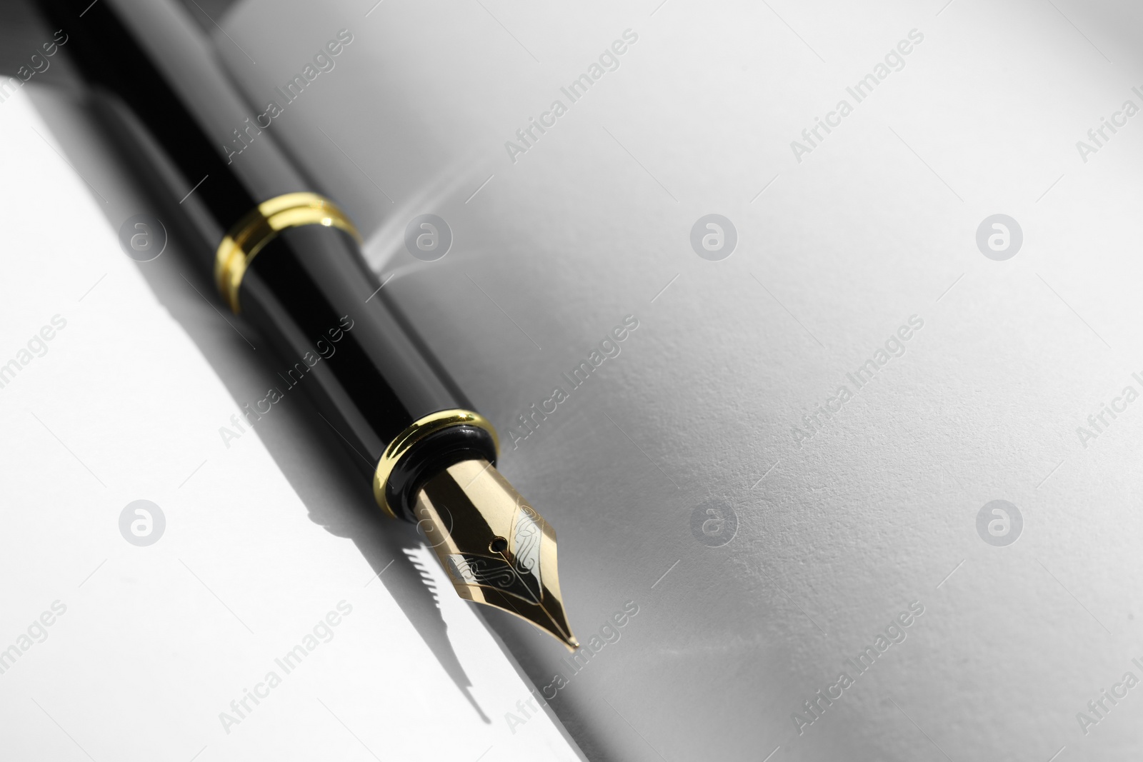 Photo of Stylish black fountain pen on open notebook, closeup. Space for text