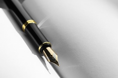 Stylish black fountain pen on open notebook, closeup. Space for text