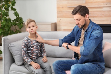 Man checking little boy's pulse with fingers at home