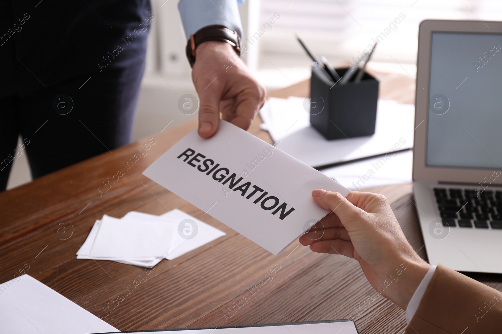 Photo of Employee giving resignation letter to boss in office, closeup