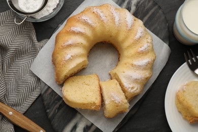 Delicious freshly baked sponge cake served on black table, flat lay