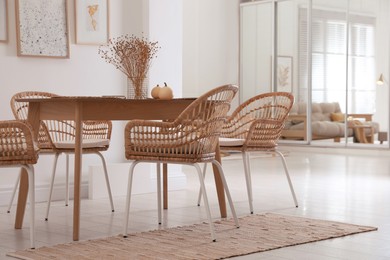 Photo of Dining room interior with wooden table and wicker chairs