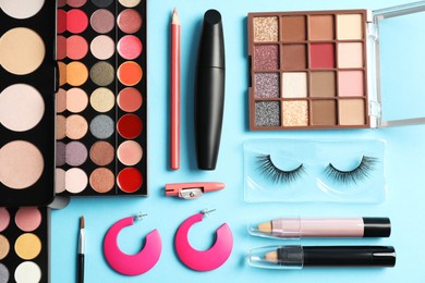 Photo of Set of makeup products and earrings on light blue background, flat lay