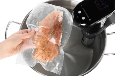 Woman putting vacuum packed meat into pot with sous vide cooker on white background, top view. Thermal immersion circulator