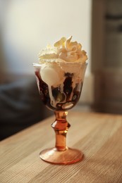 Delicious dessert with whipped cream in glass on wooden table indoors