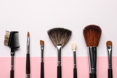 Different makeup brushes on color background, flat lay