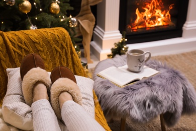 Photo of Woman in warm slippers resting on sofa at home, closeup