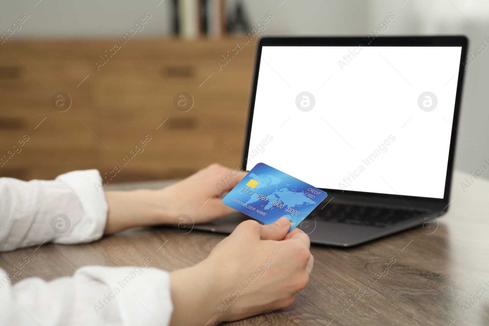 Photo of Woman with credit card using laptop for online shopping at wooden table indoors, closeup