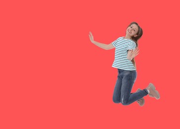 Image of Cute girl jumping on red background, space for text