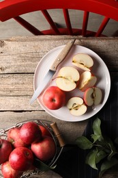 Photo of Fresh red apples, leaves and knife on wooden table, flat lay