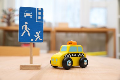 Photo of Miniature road sign and car on wooden table, closeup. Montessori toy