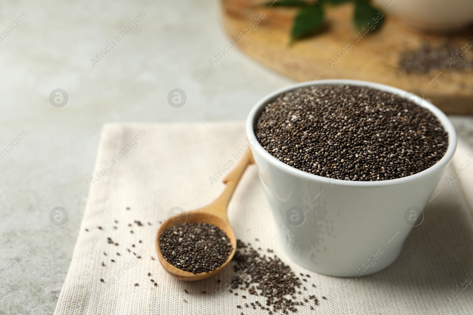 Photo of Chia seeds in bowl and spoon on table. Space for text