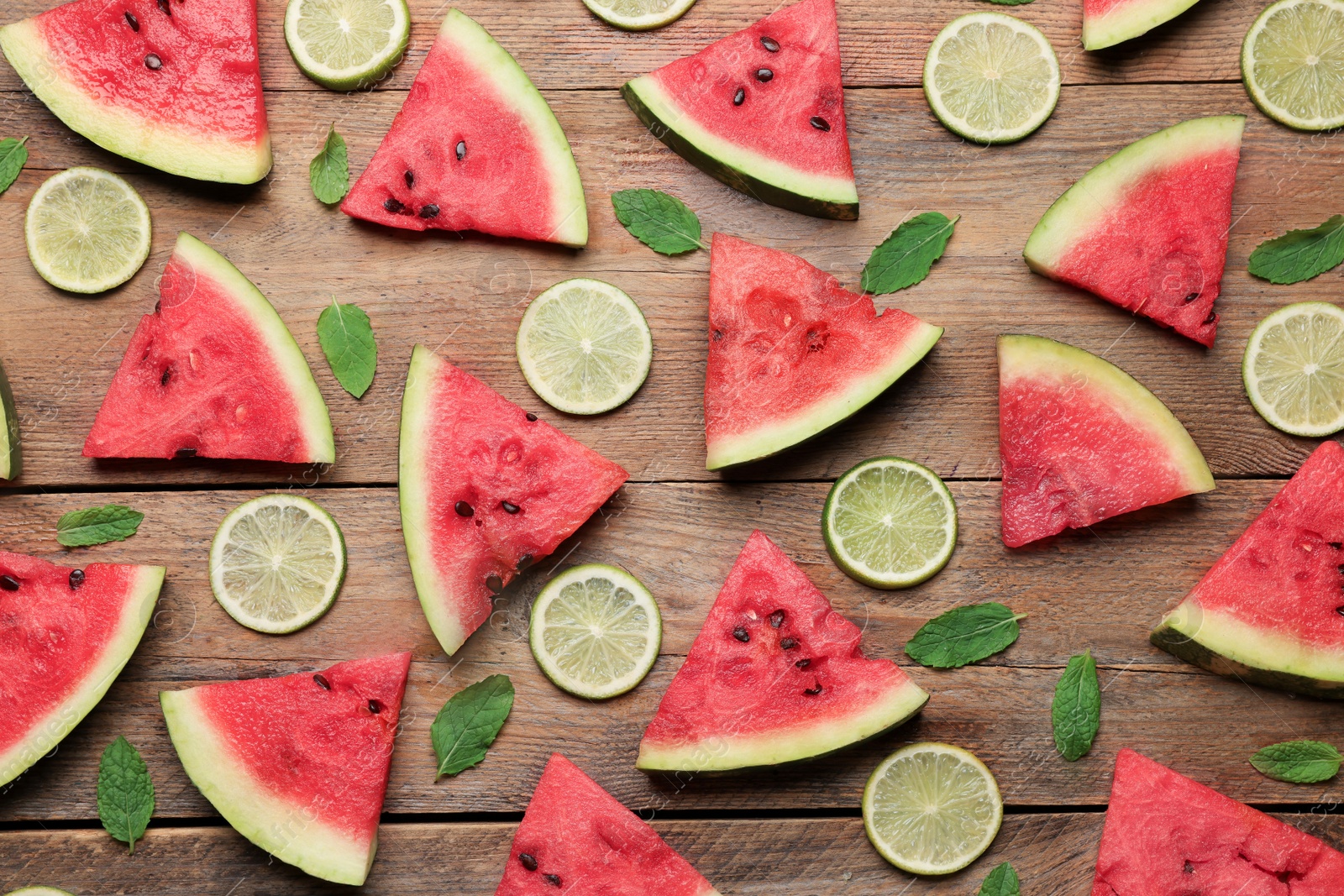 Photo of Tasty sliced watermelon and limes on wooden table, flat lay