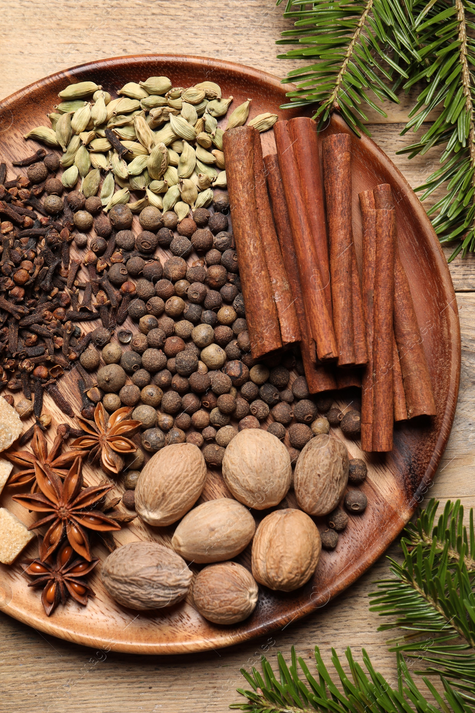 Photo of Different spices, nuts and fir branches on wooden table, flat lay