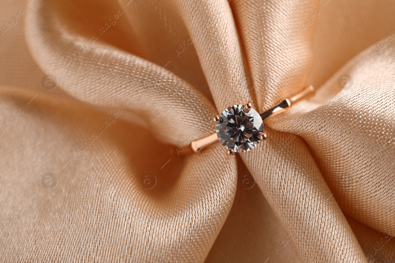 Photo of Beautiful engagement ring with gemstone on beige fabric, top view
