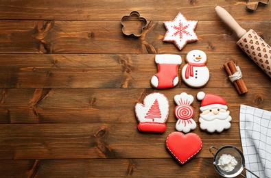 Photo of Kitchen utensils near Christmas tree shape made of delicious gingerbread cookies on wooden table, flat lay. Space for text