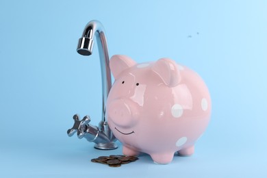 Photo of Water scarcity concept. Piggy bank, tap and coins on light blue background