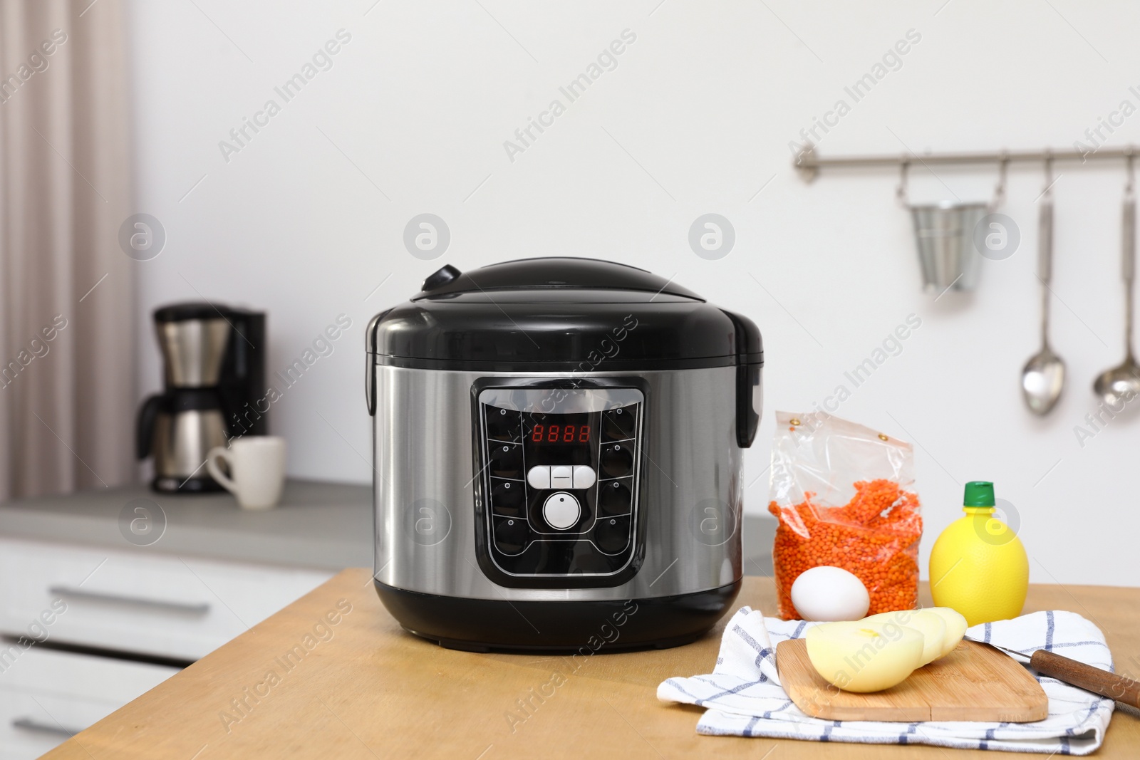 Photo of New modern multi cooker and products on table in kitchen