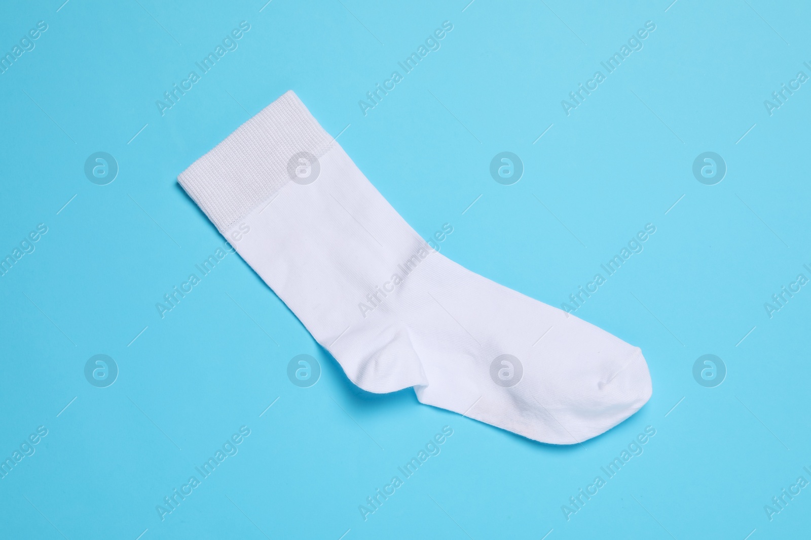Photo of New white sock on light blue background, top view