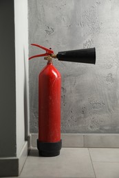 Photo of Fire extinguisher on floor near grey wall indoors