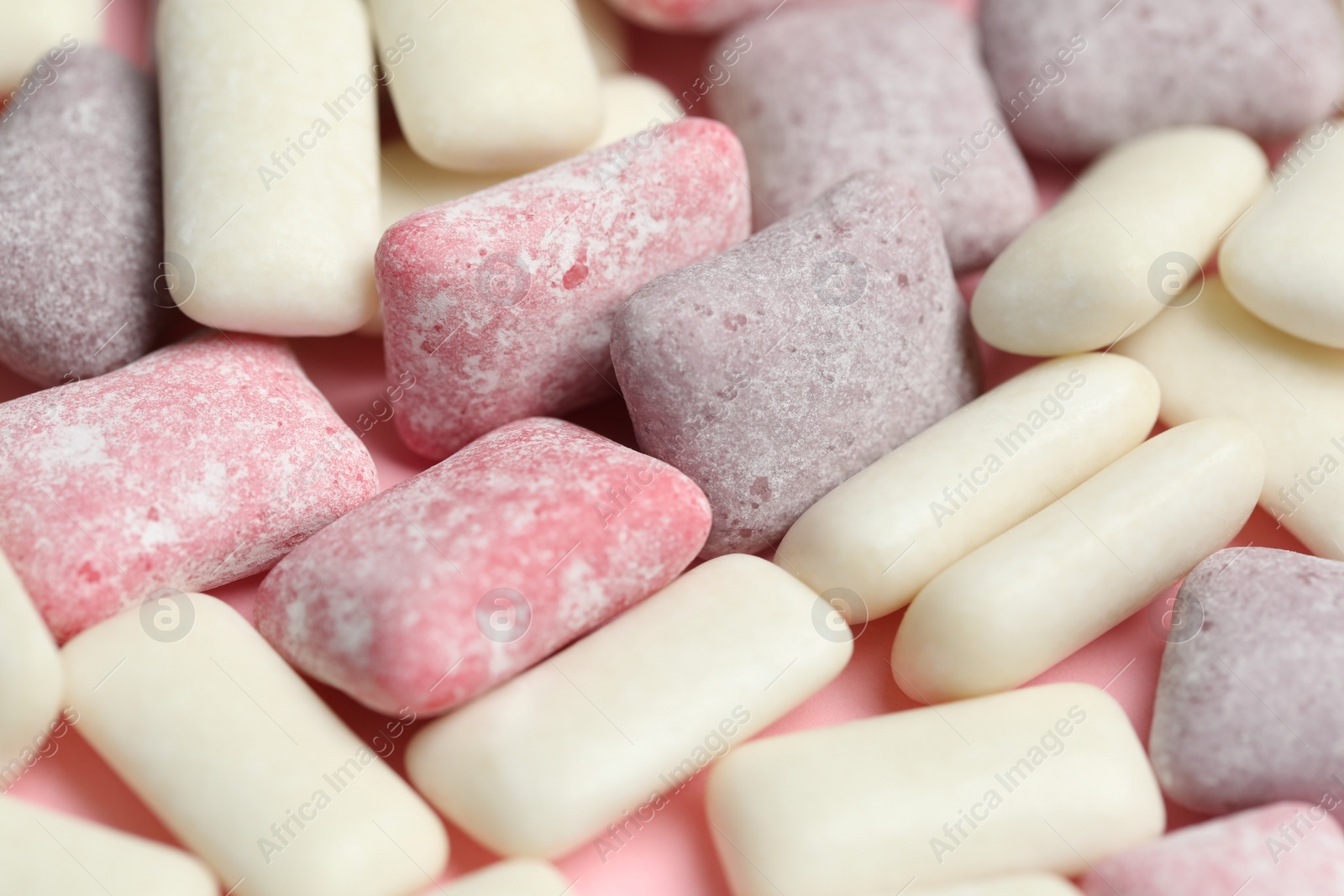 Photo of Different tasty colorful bubble gums on pink background, closeup