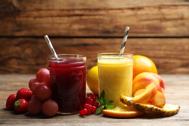 Photo of Delicious colorful juices in glasses and fresh ingredients on wooden table